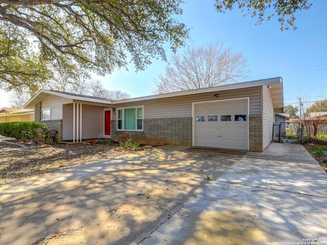 ranch-style home featuring a gate, fence, concrete driveway, an attached garage, and brick siding