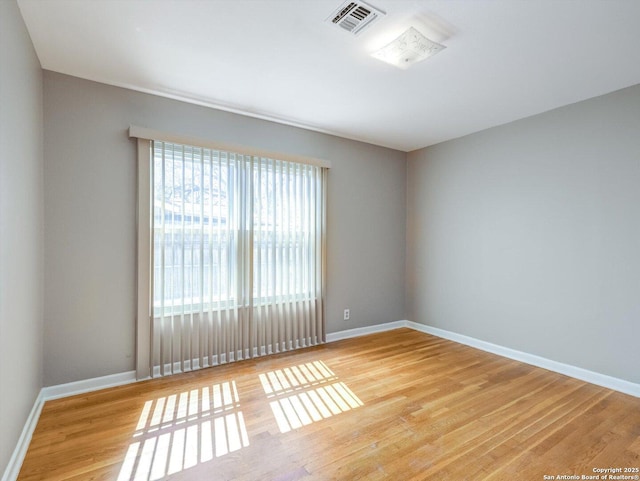 spare room with visible vents, light wood-type flooring, and baseboards