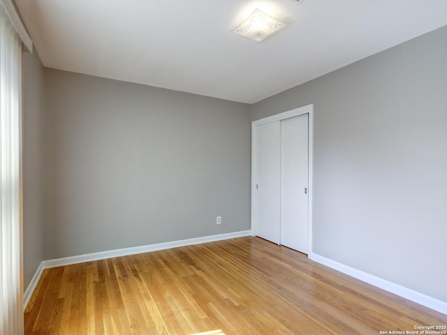 unfurnished bedroom with a closet, baseboards, and light wood-style floors