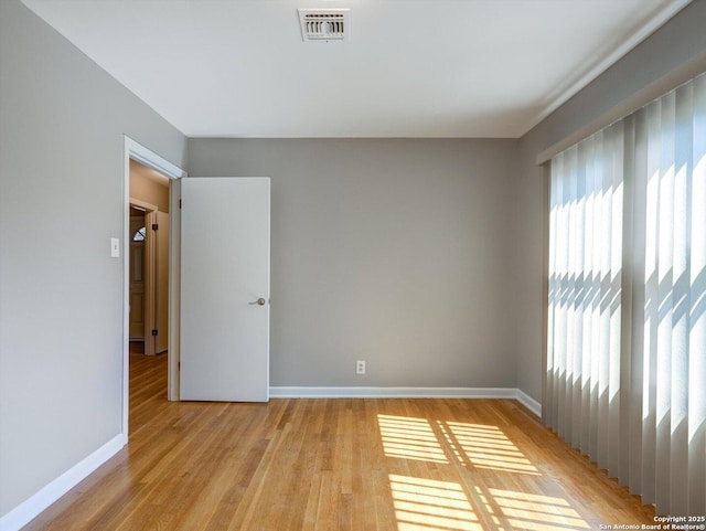 spare room with light wood-style flooring, baseboards, and visible vents