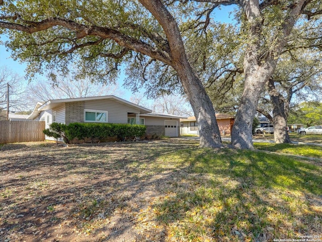 view of property exterior with a garage, a lawn, and fence