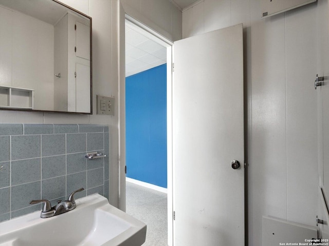 bathroom featuring decorative backsplash, tile walls, and a sink