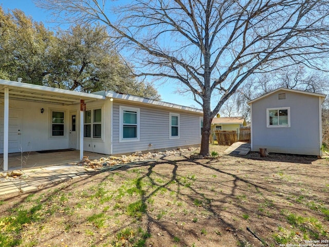 exterior space featuring a patio area, fence, and an outbuilding