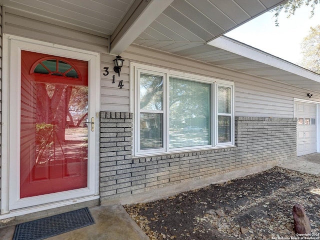 view of exterior entry featuring brick siding