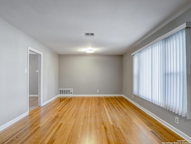 spare room with visible vents, baseboards, and light wood finished floors