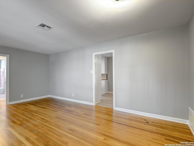 empty room featuring visible vents, baseboards, and light wood-style floors