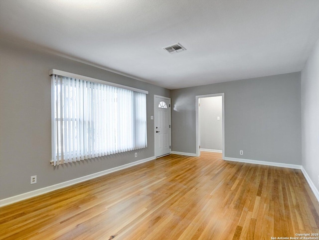 spare room featuring light wood-style flooring, baseboards, and visible vents