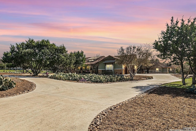 view of front of home featuring stone siding and curved driveway