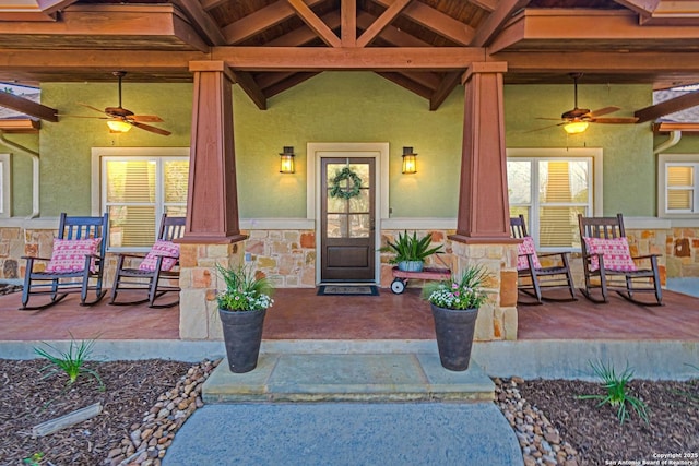 property entrance featuring covered porch, stone siding, and stucco siding