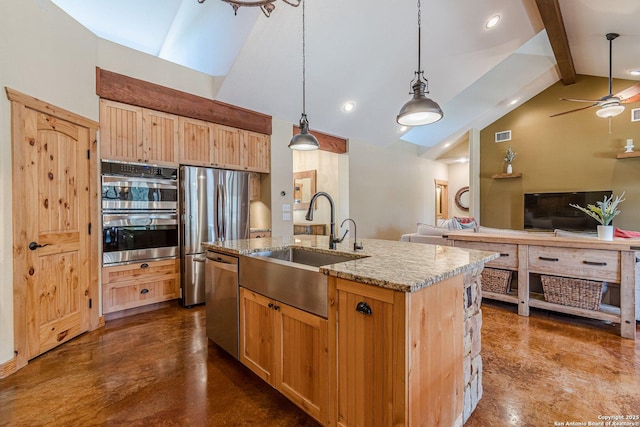 kitchen with a kitchen island with sink, a sink, light stone counters, open floor plan, and stainless steel appliances