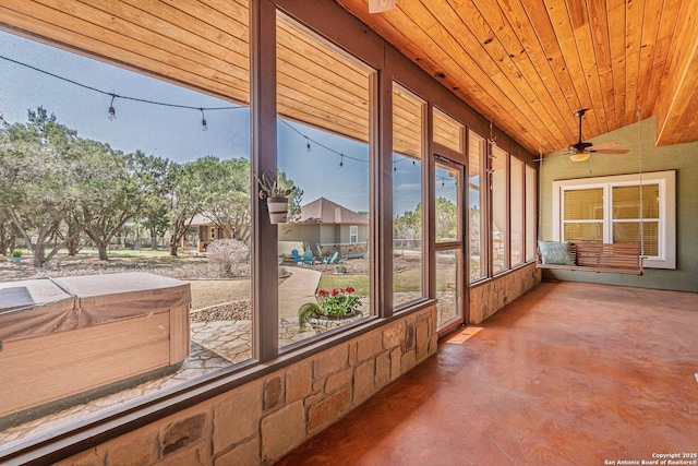 unfurnished sunroom featuring lofted ceiling, wood ceiling, and a ceiling fan