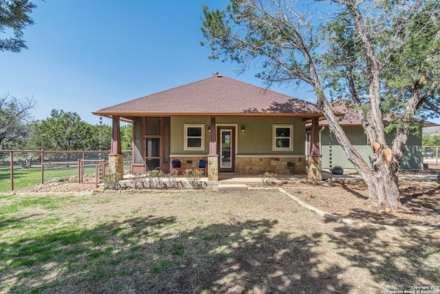 back of house with fence, a porch, a lawn, stucco siding, and stone siding