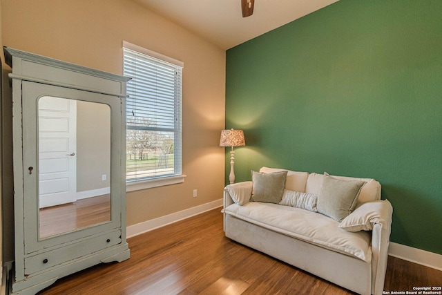 sitting room with baseboards, wood finished floors, and a ceiling fan