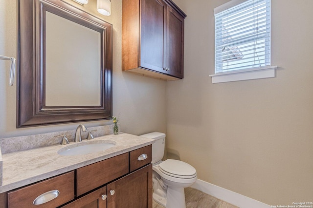 half bathroom with toilet, vanity, and baseboards