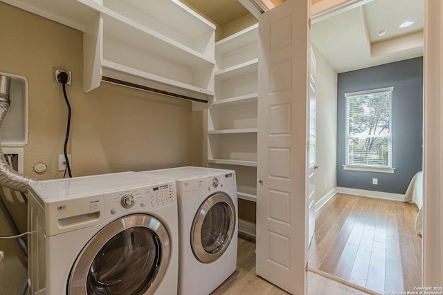 clothes washing area with washer and clothes dryer, laundry area, light wood-type flooring, and baseboards