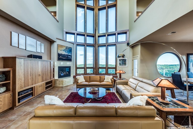 living room with a tiled fireplace, visible vents, and a towering ceiling