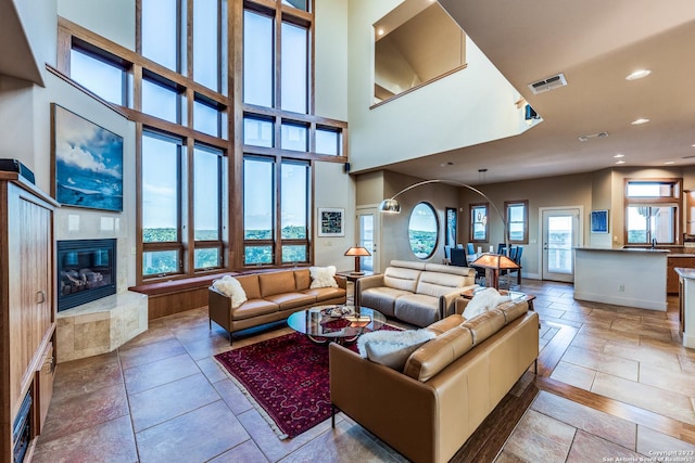 living area with a high ceiling, recessed lighting, a fireplace, and visible vents