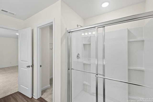 bathroom featuring visible vents, a walk in closet, baseboards, a stall shower, and wood finished floors