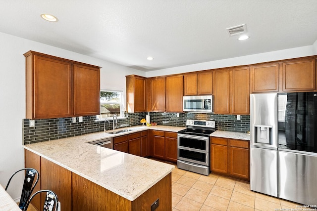 kitchen featuring visible vents, brown cabinets, appliances with stainless steel finishes, and a sink