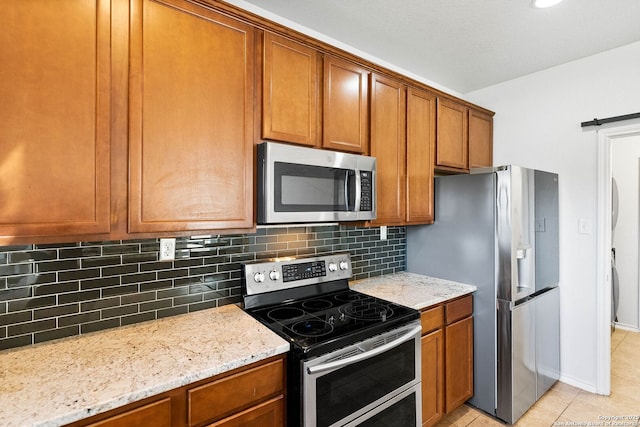 kitchen featuring stainless steel appliances, light stone countertops, and brown cabinetry