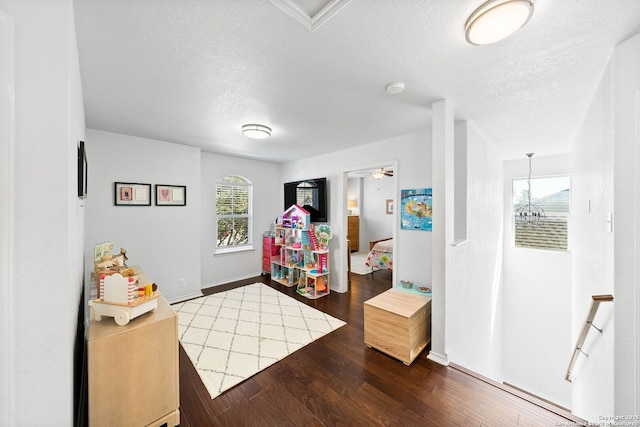 playroom featuring a healthy amount of sunlight, a textured ceiling, and wood finished floors