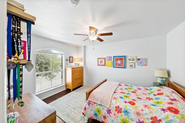 bedroom featuring baseboards, a textured ceiling, and ceiling fan