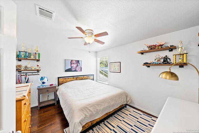 bedroom featuring a ceiling fan, baseboards, wood finished floors, visible vents, and a textured ceiling