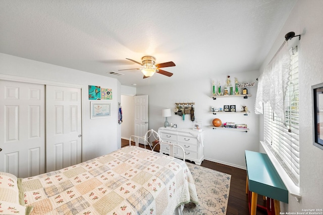 bedroom featuring visible vents, a ceiling fan, a textured ceiling, a closet, and dark wood-style flooring