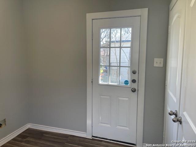 doorway with dark wood-style floors and baseboards