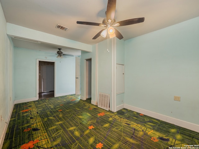 carpeted spare room with visible vents, baseboards, and ceiling fan