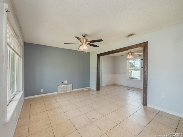 unfurnished room with visible vents, a textured ceiling, ceiling fan, and light tile patterned flooring