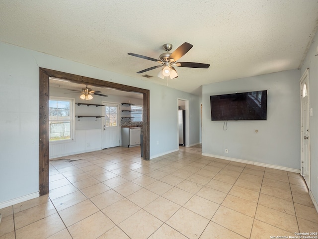 unfurnished living room featuring visible vents, baseboards, ceiling fan, light tile patterned flooring, and a textured ceiling