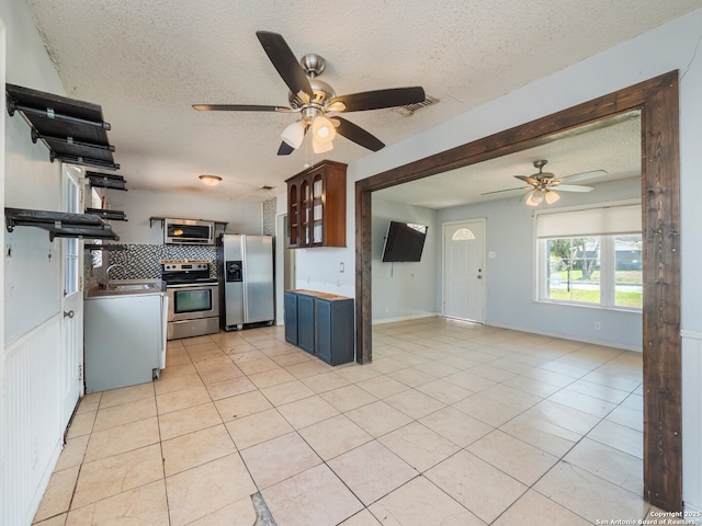 kitchen featuring visible vents, a ceiling fan, a sink, backsplash, and stainless steel appliances