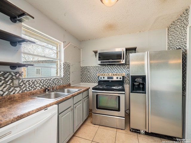 kitchen with a sink, backsplash, appliances with stainless steel finishes, and open shelves