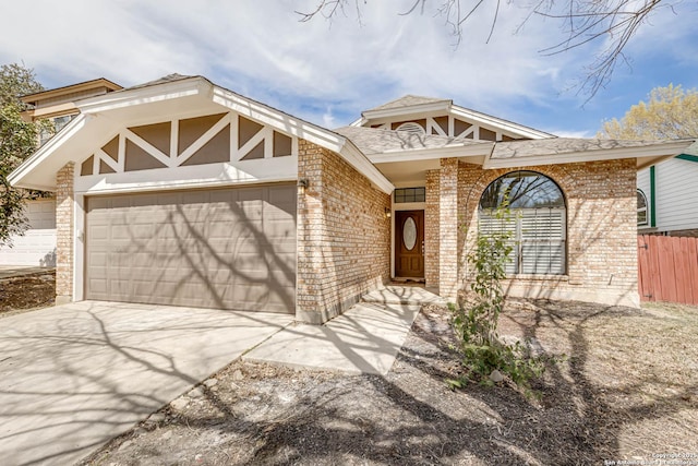 view of front of home featuring driveway, brick siding, an attached garage, and fence