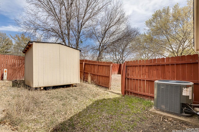 view of yard with an outdoor structure, central AC unit, a fenced backyard, and a shed