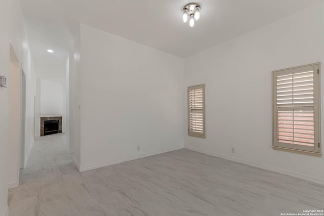 unfurnished room with a fireplace and baseboards