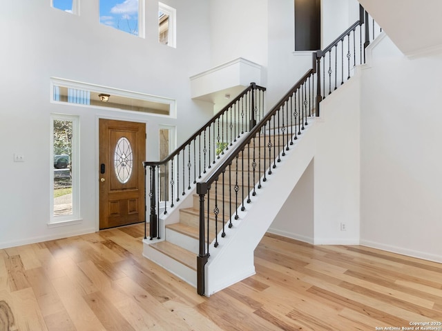 entrance foyer featuring a high ceiling, stairs, baseboards, and wood finished floors