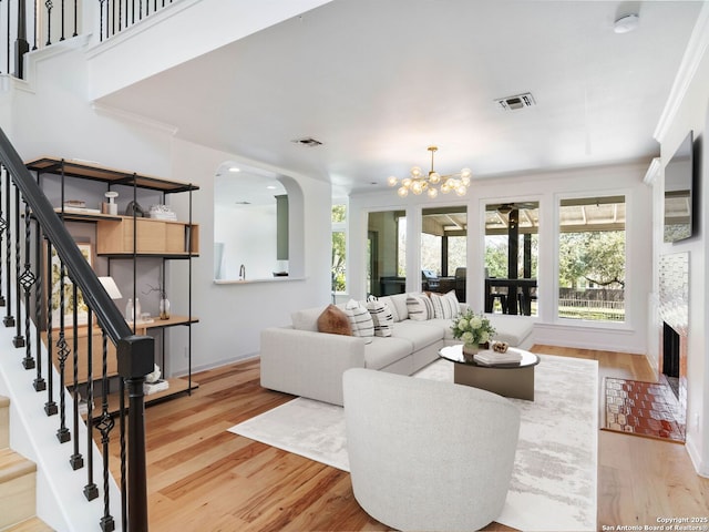 living room with an inviting chandelier, stairway, visible vents, and light wood finished floors