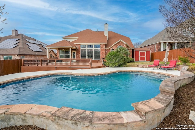 view of swimming pool featuring an outbuilding, fence, a storage shed, a wooden deck, and a fenced in pool