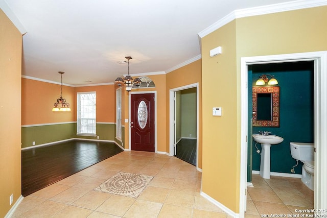 entrance foyer featuring light tile patterned flooring, a notable chandelier, and crown molding