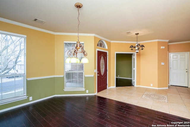 interior space featuring visible vents, crown molding, baseboards, wood finished floors, and a notable chandelier