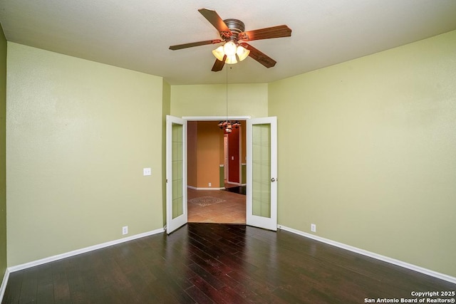 empty room with french doors, baseboards, wood finished floors, and ceiling fan with notable chandelier