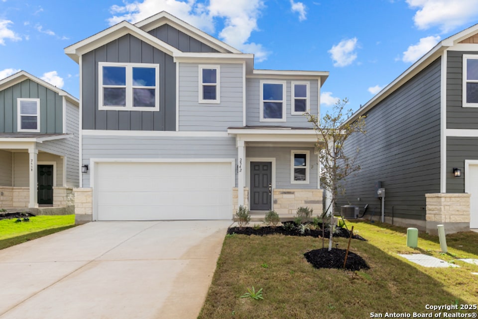 craftsman inspired home with board and batten siding, a front lawn, concrete driveway, a garage, and stone siding