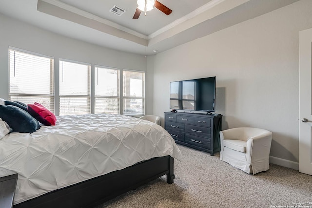 bedroom with a raised ceiling, light colored carpet, visible vents, and ornamental molding