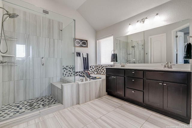 bathroom featuring a garden tub, a sink, a shower stall, double vanity, and lofted ceiling