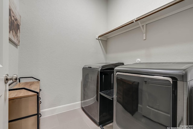 clothes washing area featuring tile patterned floors, laundry area, washer and dryer, and baseboards