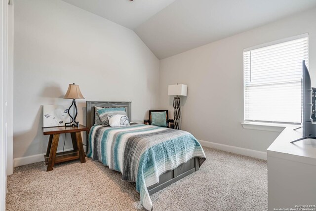 bedroom with vaulted ceiling, light colored carpet, and baseboards