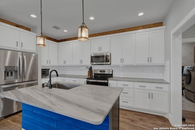 kitchen with a sink, stainless steel appliances, light stone counters, and wood finished floors