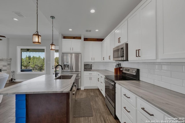 kitchen featuring visible vents, backsplash, appliances with stainless steel finishes, a ceiling fan, and a sink